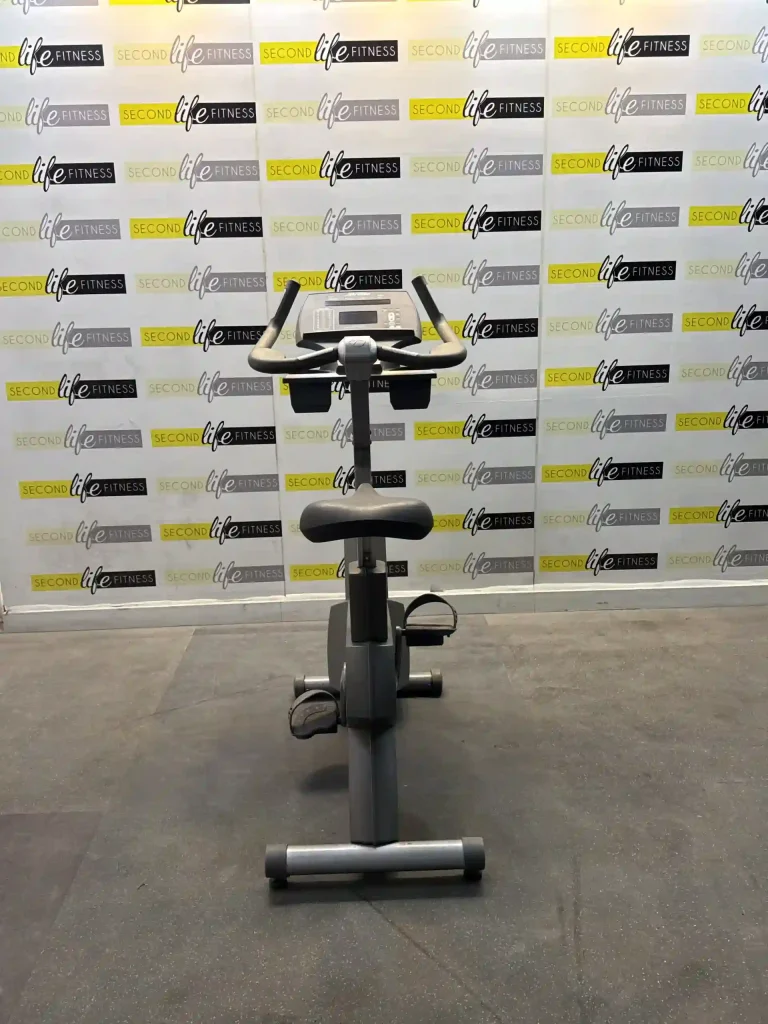 A person comfortably exercising on the Life Fitness Upright Bike in a modern Dubai apartment gym, highlighting the large 16" touchscreen display showing a fitness program. The image emphasizes the user-friendly interface and the integration of technology into home workouts in the UAE.