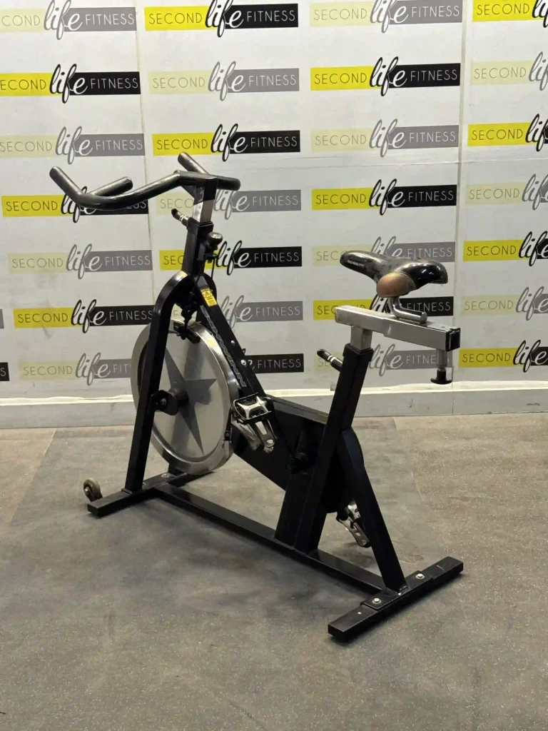 A person intensely working out on the Professional Indoor Cycling Bike in a modern Dubai home gym, highlighting the 16" touchscreen display showing a TV program. The image emphasizes the engaging entertainment and the robust build quality for home users in the UAE.
